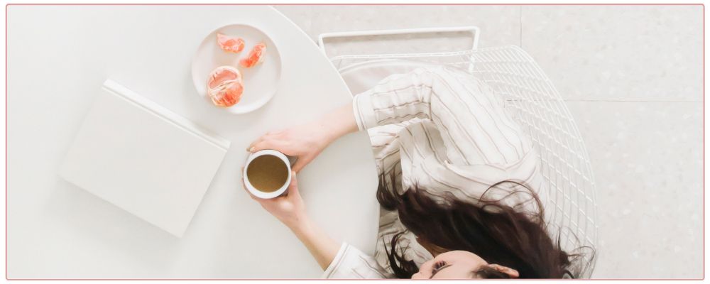 Woman sitting at a table with a cup of coffee and oranges, talking to her business coach.